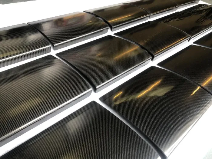 Rows of finished gloss carbon fibre panels laid out for inspection