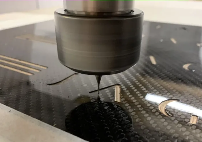 CNC spindle cutting a sheet of cured carbon fibre